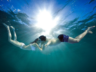 Young guy and girl kiss underwater - romantic scene.