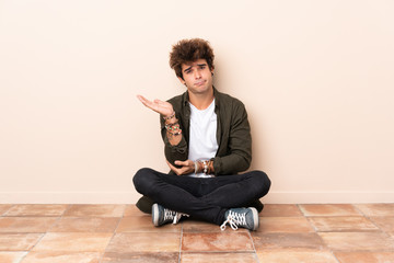 Young caucasian man sitting on the floor unhappy for not understand something