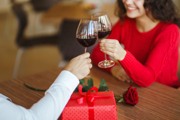 Young couple having a romantic dinner and toasting with glass of red wine. Sweet couple celebrate their anniversary. Valentines day celebration concept. Relationship, surprise and love concept.