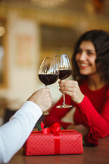 Young couple having a romantic dinner and toasting with glass of red wine. Sweet couple celebrate their anniversary. Valentines day celebration concept. Relationship, surprise and love concept.