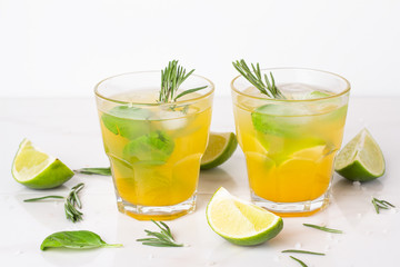 refreshing drink with lime ice and rosemary in a glass on a white background