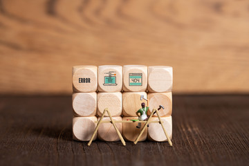 little painter figure and wooden blocks with error icons on wooden background