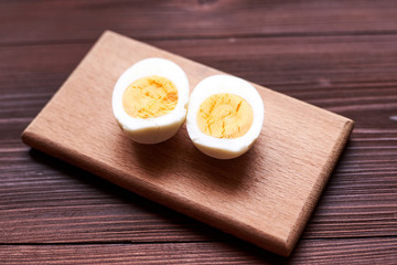 Boiled chicken egg cut into two halves on a wooden background.