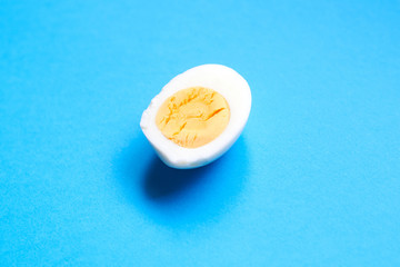 Half boiled chicken egg on a blue background.