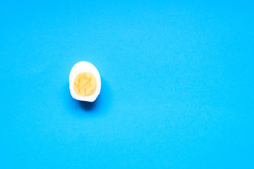 Half boiled chicken egg on a blue background.
