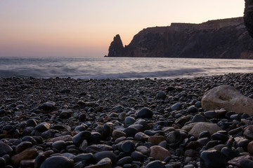 Stone beach close-up on the background of the rock going into the sea. Sunset on the beach Fiolent.