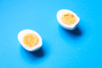 Boiled chicken egg cut into two halves on a blue background.