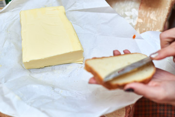 Woman smears butter on bread. Making a sandwich.