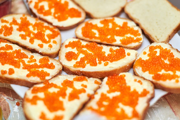 Cooked sandwiches with red salmon caviar on the table.