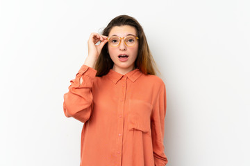 Young brunette girl over isolated white background with glasses and surprised