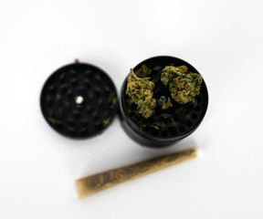 marijuana in a grinder with a joint on a white background