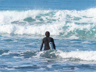 Man with a surfboard entering the sea, in Sopelana, Basque country.