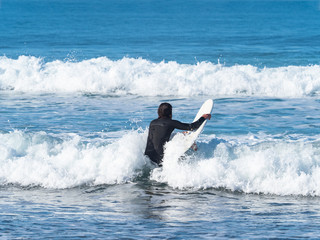 Man with a surfboard entering the sea, in Sopelana, Basque country.