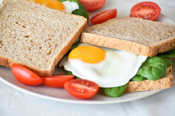 Sandwich with egg, spinach and tomato on a plate. Selective focus.