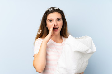 Young woman in pajamas over isolated blue background shouting with mouth wide open