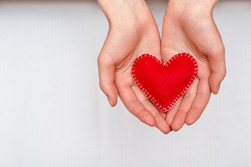 Handmade red heart in the hands of a girl on a white background with copy space. Valentine's Day, Mother's Day