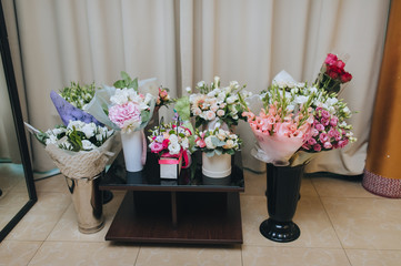 Freshly packed flowers stand in vases and boxes. Gifts from guests to the newlyweds for the wedding. Holiday birthday gifts.