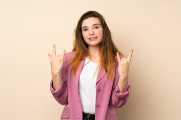 Young brunette girl with blazer over isolated background making rock gesture