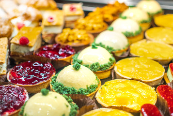 Pastry shop with variety of donuts, muffins, creme brulee, cakes with fruits and berries
