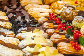 Pastry shop with variety of donuts, muffins, creme brulee, cakes with fruits and berries