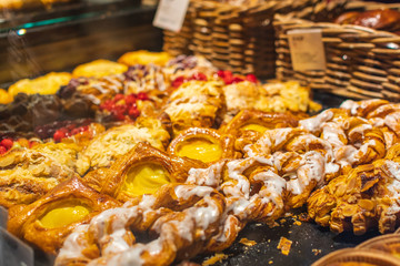 Pastry shop with variety of donuts, muffins, creme brulee, cakes with fruits and berries