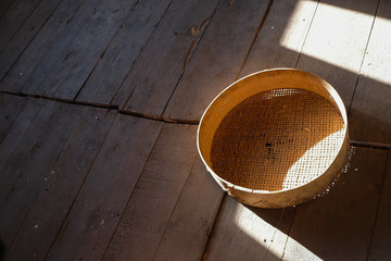 Rustic still life with empty old sieve and geometric shadows on a rough wooden surface. 