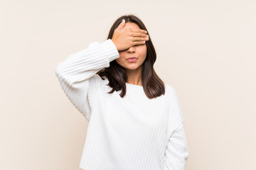 Young brunette woman with white sweater over isolated background covering eyes by hands