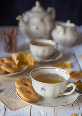Tazze di tè con teiera e piatto di biscotti