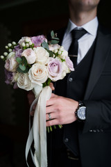 Obraz na płótnie Canvas Groom holding a wedding bouquet. . Stylish groomsmen. Businessman. Luxury man in suit in room. Morning of the groom. Wedding day. Marriage.