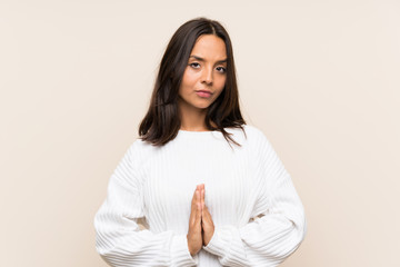 Young brunette woman with white sweater over isolated background pleading