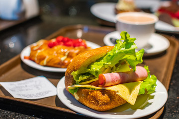 Fresh burger with coffee and some pastry in cafe.