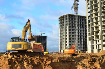 Excavator load the sand to the heavy dump truck on construction site. Excavators and dozers digs the ground for the foundation and construction of a new building. Apartment renovation program