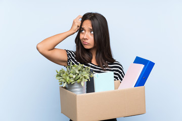Young brunette girl making a move while picking up a box full of things having doubts and with...