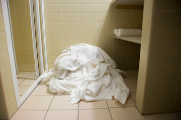 Pile of dirty used towels on the hotel bathroom floor. Housekeeping replace only the used towels on...