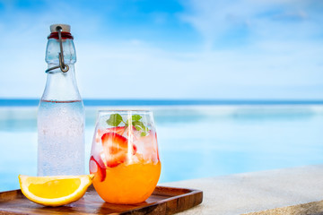 orange italian soda with fresh strawberry on pool side