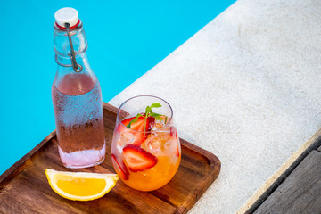 orange italian soda with fresh strawberry on pool side