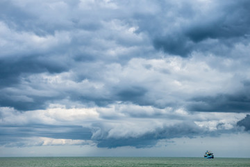 small fishing boat in open sen against cloudy weather © amfroey01