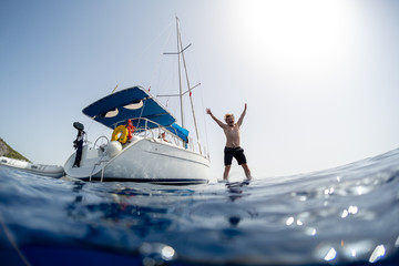 Young man jumps into the sea from the sail boat