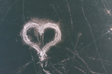 An ice heart drawn by skates on the surface of a frozen lake. The view from the top.