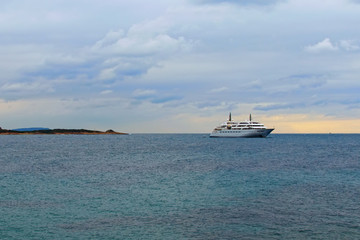 Fototapeta na wymiar The large modern white private yacht moored in the Saronic Gulf. Travel and tourism concept. Cloudy sky in the background. Landscape panoramic view. Athens, Greece