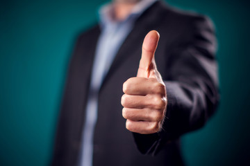 Businessman in suit showing thumb up gesture. Success concept