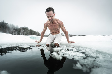 Young man prepares to swim in the ice hole made on the winter lake