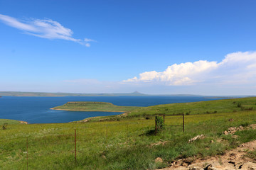 Sterkfontein Dam looking blue and full with green grass on a summers day in the wilderness of the Orange Free State near Golden Gate Highlands National Park