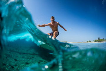 Fototapeta na wymiar Surfer rides ocean wave in tropics