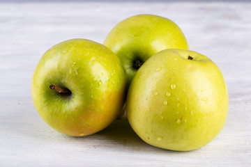 Yellow apples on white wooden background