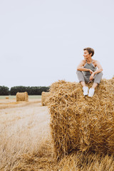 Naklejka na ściany i meble lifestyle girl sitting round haystack field harvest