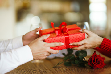 Valentine's Day, holiday and surprise concept. Man gives to his woman a red gift box. Sweet couple...