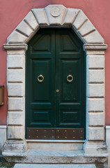 Green wood door with marble portal in Carrara, Tuscany