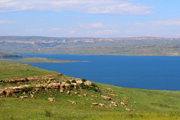 Sterkfontein Dam looking blue and full with green grass on a summers day in the wilderness of the Orange Free State near Golden Gate Highlands National Park