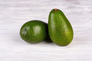 Green avocado on white wooden background